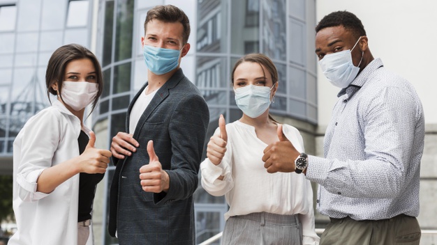 coworkers-outdoors-during-pandemic-wearing-masks-giving-thumbs-up
