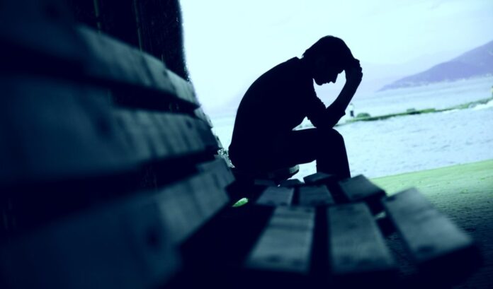Young man sitting looking upset