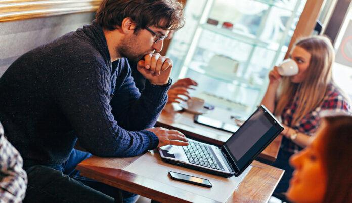 Young Man Using Laptop In Cafe