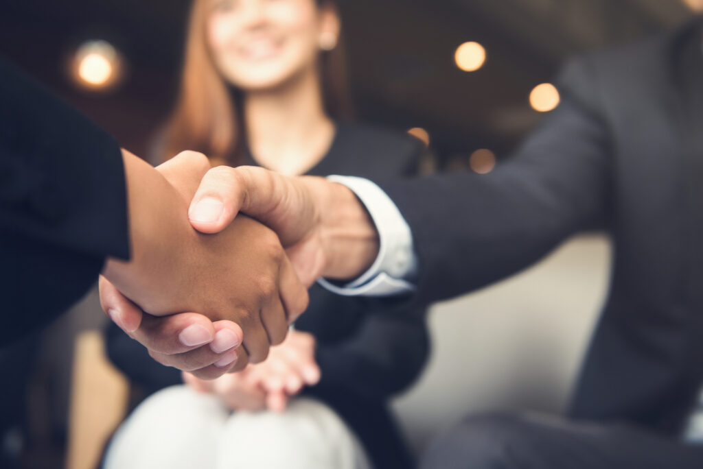 Businessmen making handshake with his partner in cafe - depiction of a selection of an outsourcing partner