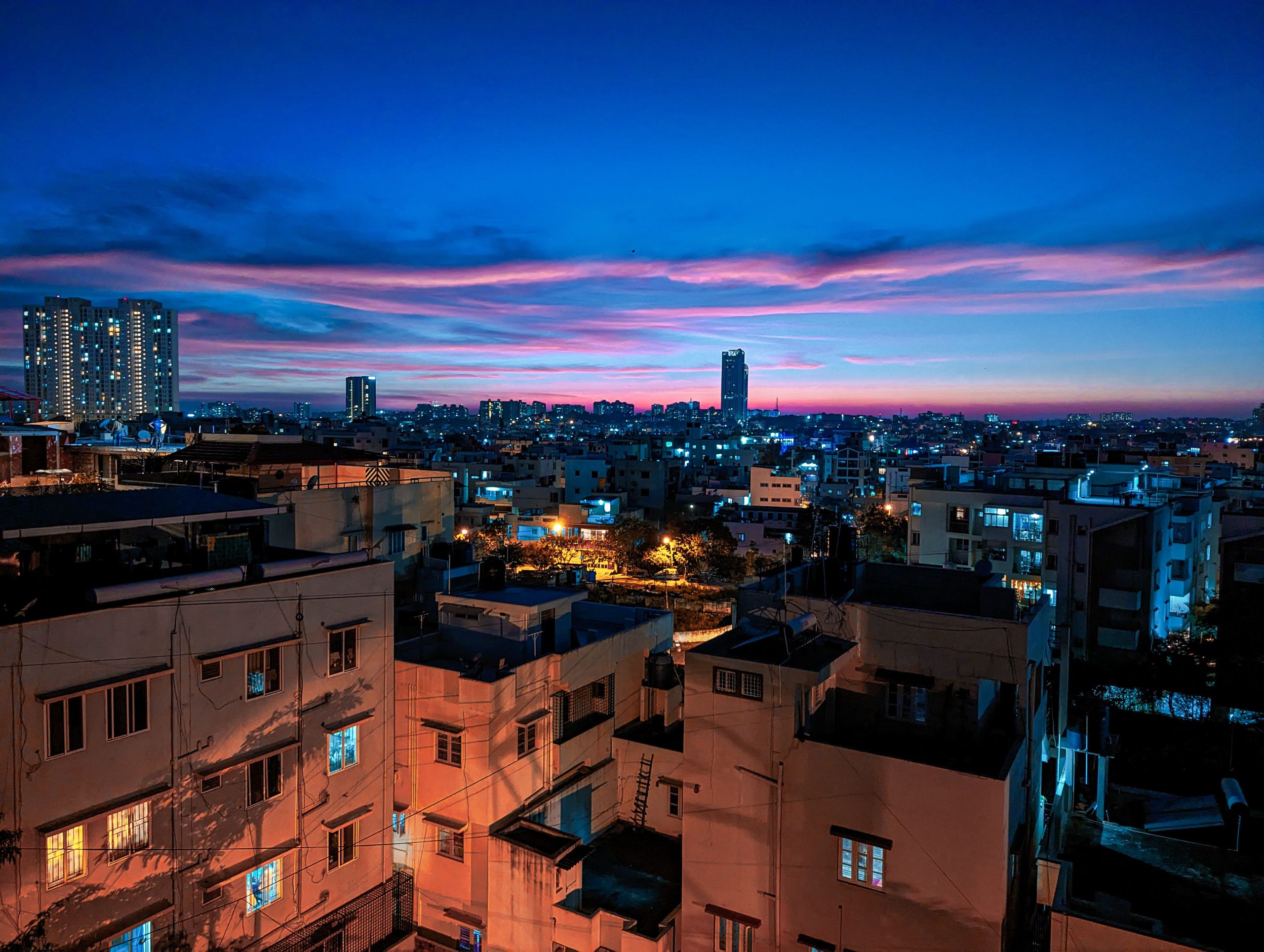 Bengaluru cityscape illuminated at dusk with modern high-rise architecture under a vivid sunset sky