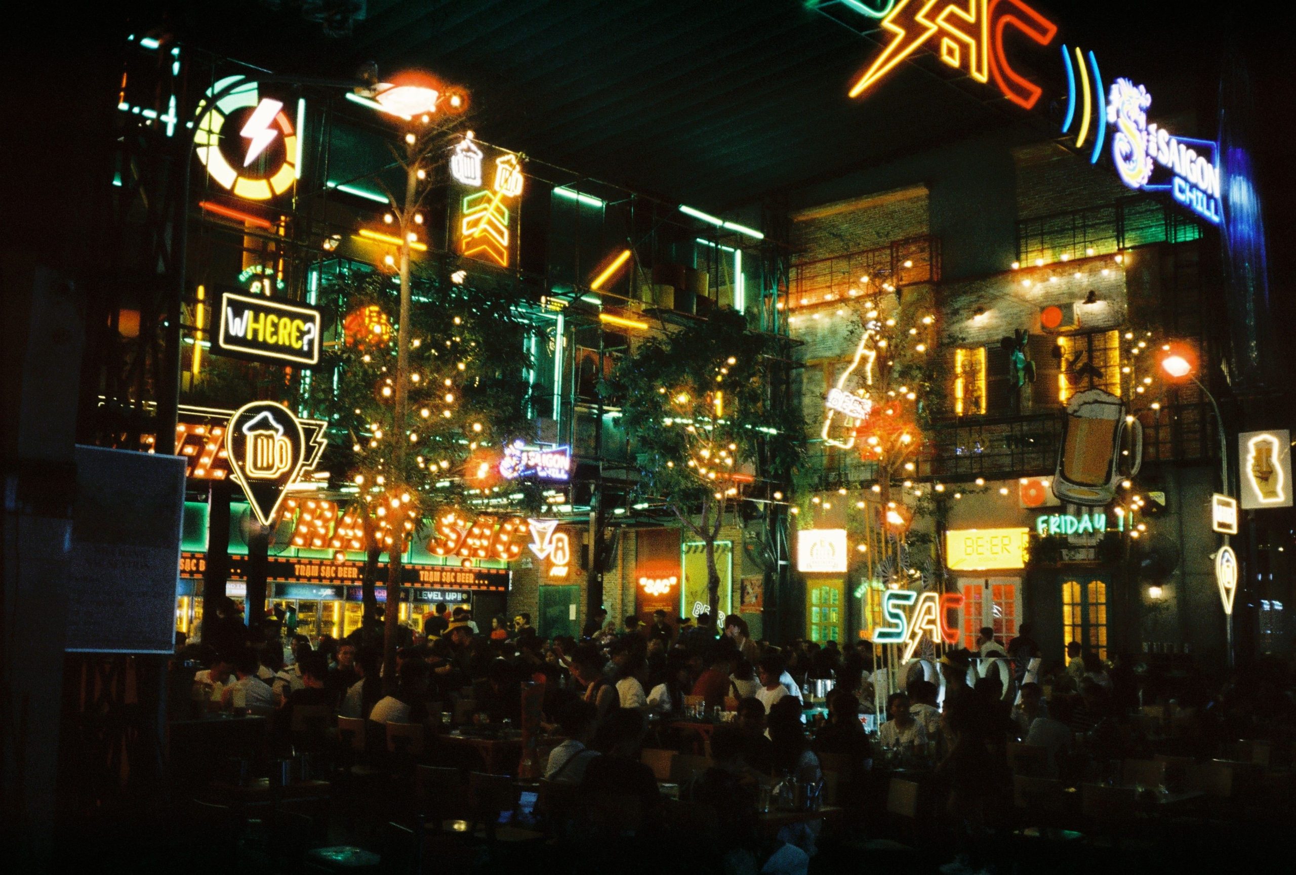 Lively city nightlife district with glowing neon bar signs and a crowded venue, capturing the energy of the best nightlife cities