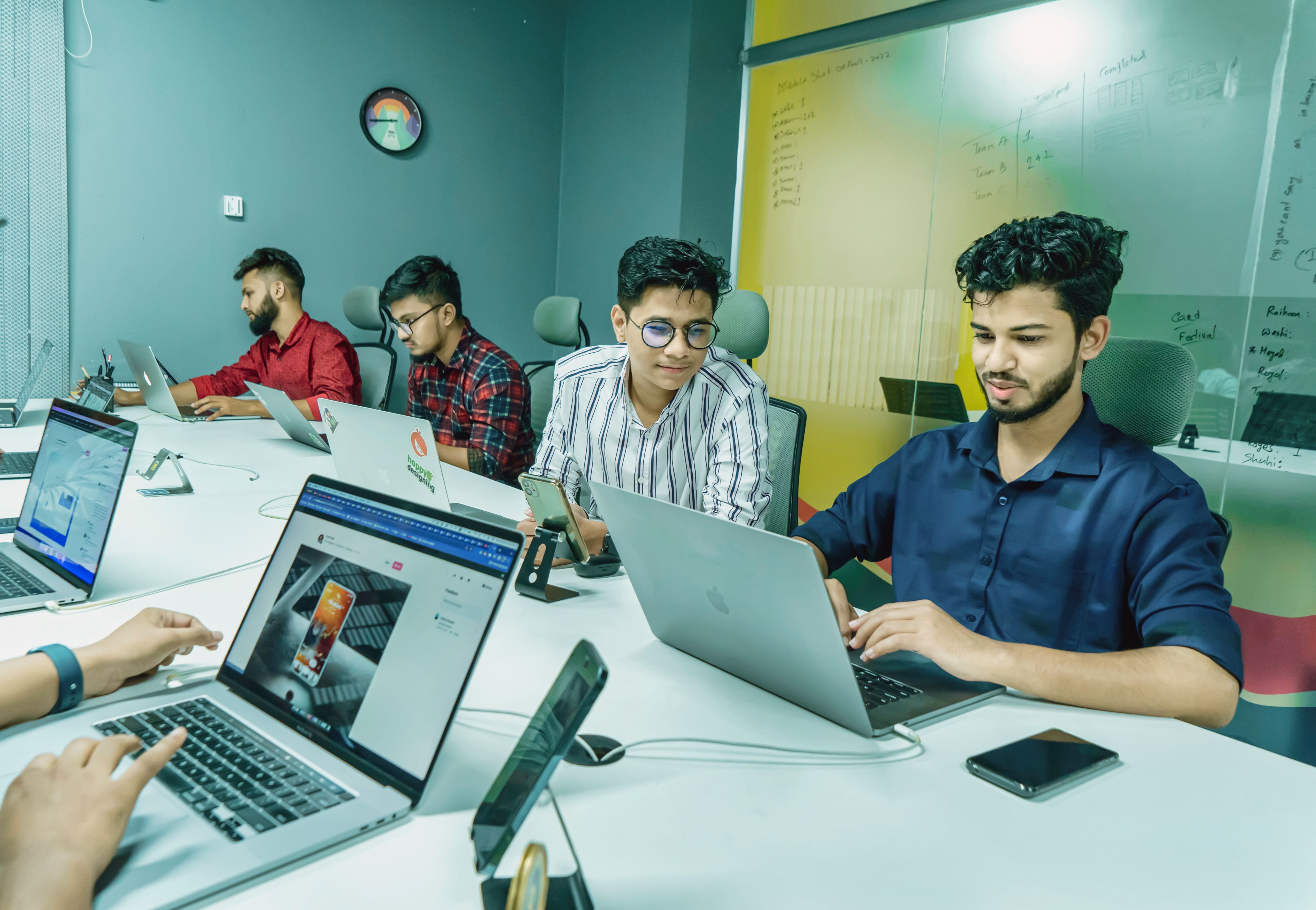 Group of young Indian professionals collaborating on laptops in a modern startup office