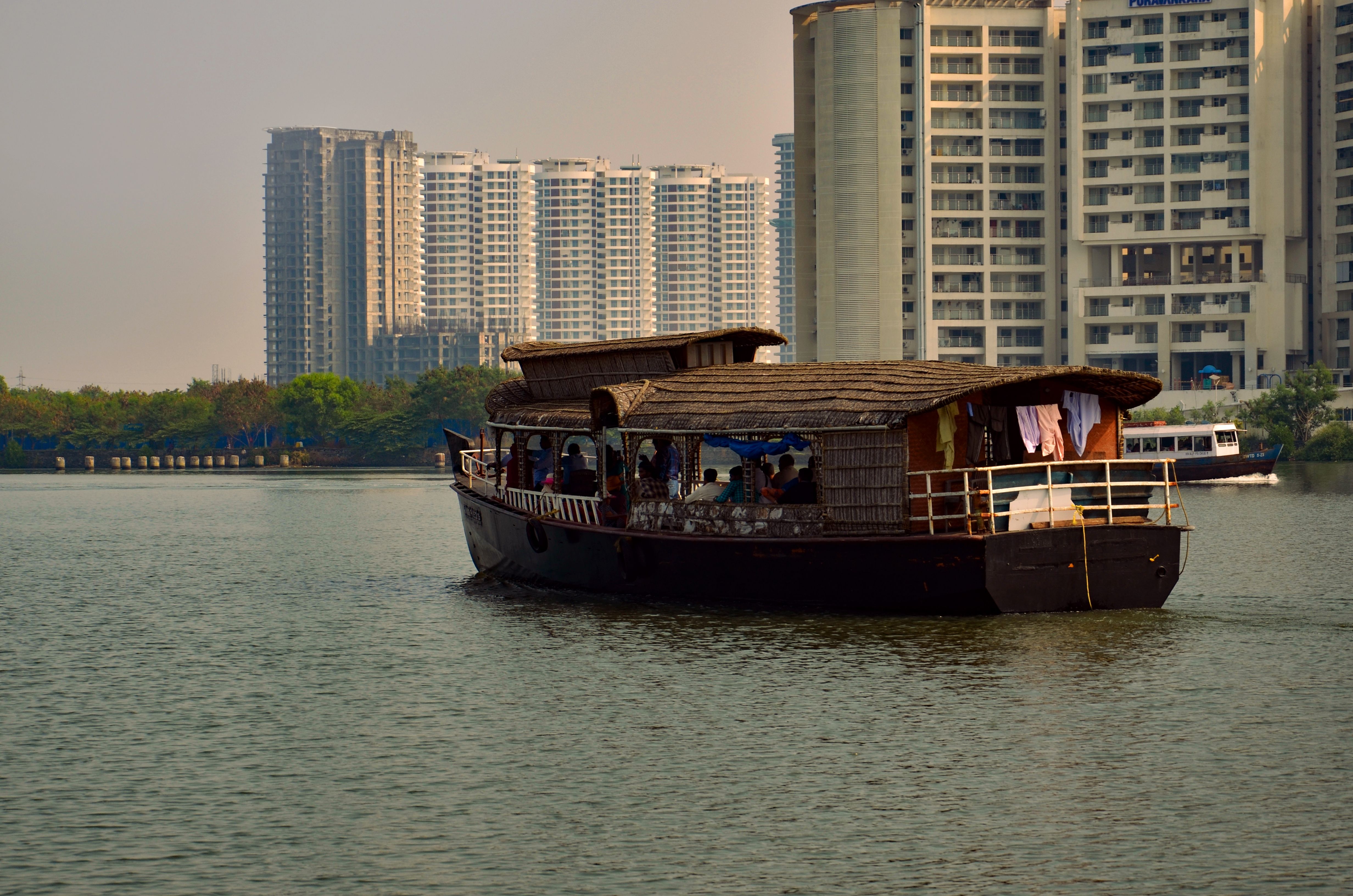 Traditional Kerala houseboat on the water with Kochi's modern city skyline in the background